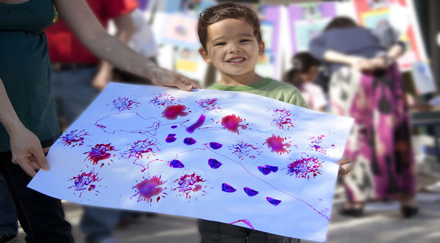 Child showing artwork at a seasonal festival