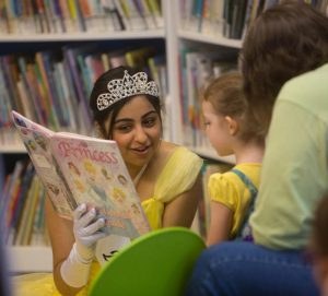 A storyteller dressed as a princess reading to children at the Literacy Tea